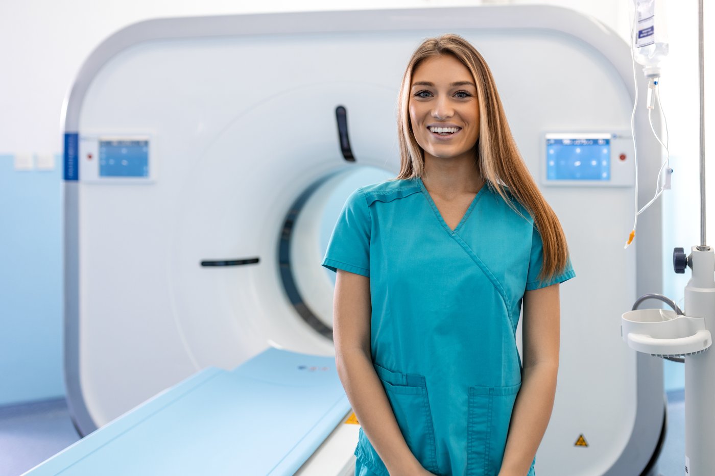 MRI Technologist in scrubs standing in front of an MRI machine